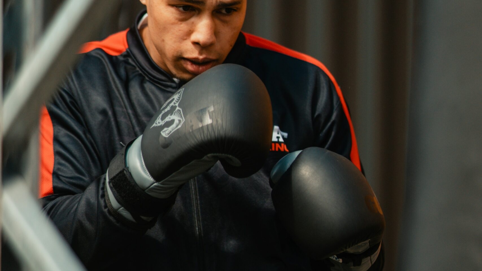 A man wearing a black jacket and boxing gloves
