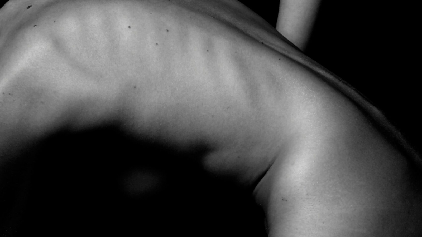 a naked woman sitting on a table with her back to the camera