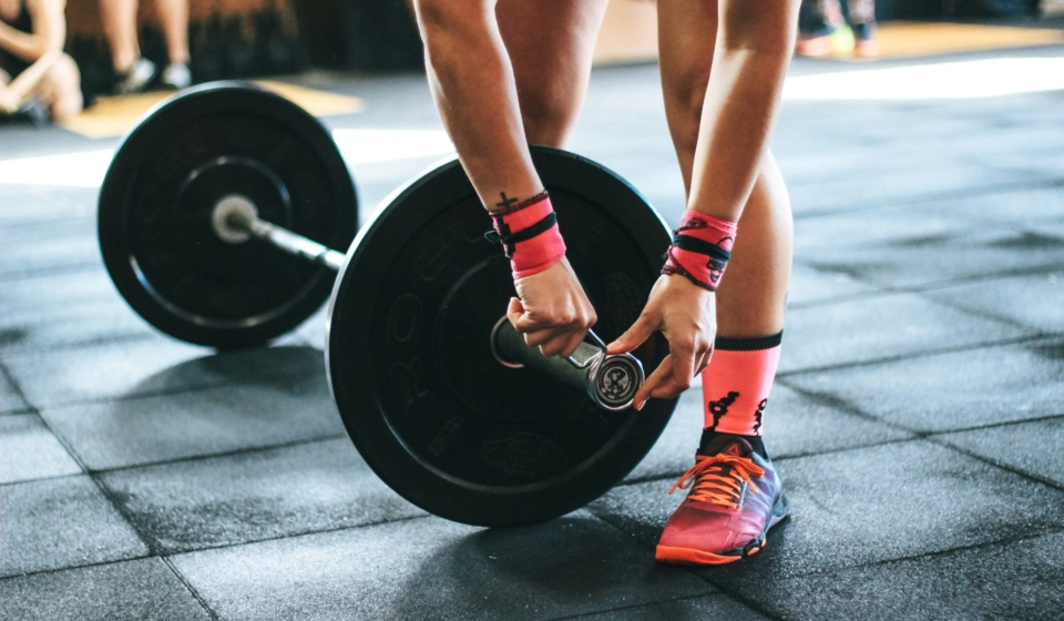 person locking gym plates on barbell