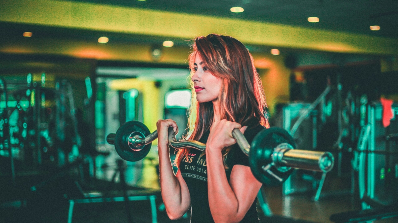 woman lifting black and gray barbell